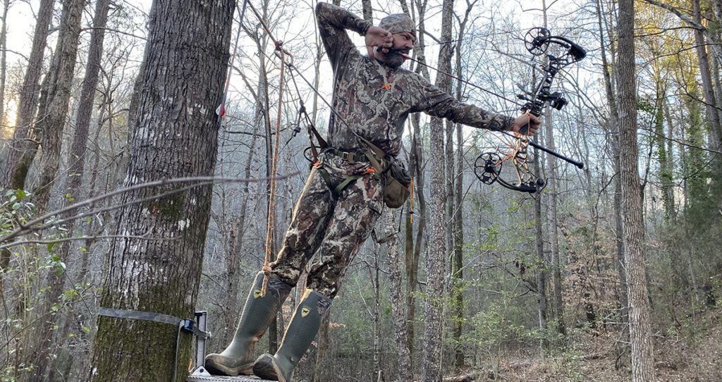 The author drawing back a bow from his hunting saddle.